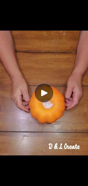 two hands are holding an orange on the floor