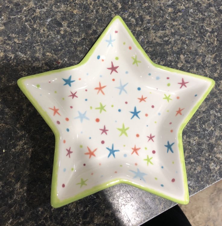 a ceramic star dish with multicolored stars on it sitting on a granite counter