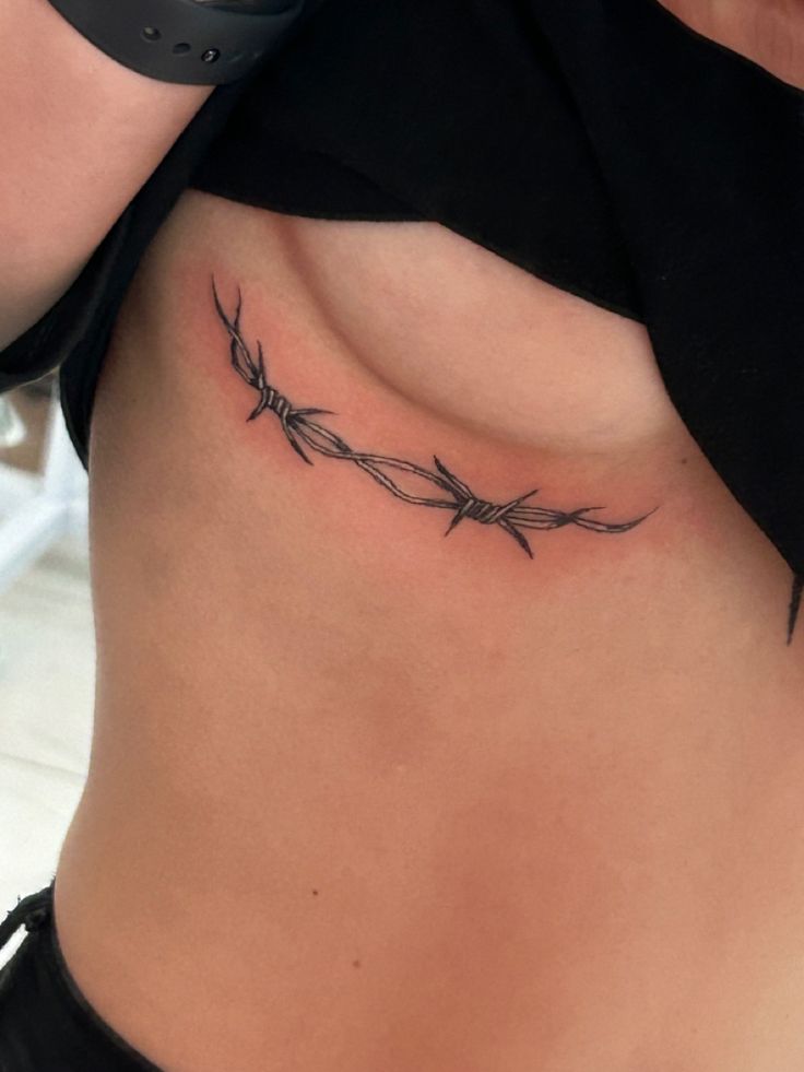 a woman's stomach with barbed wire tattoo on her side ribcadings