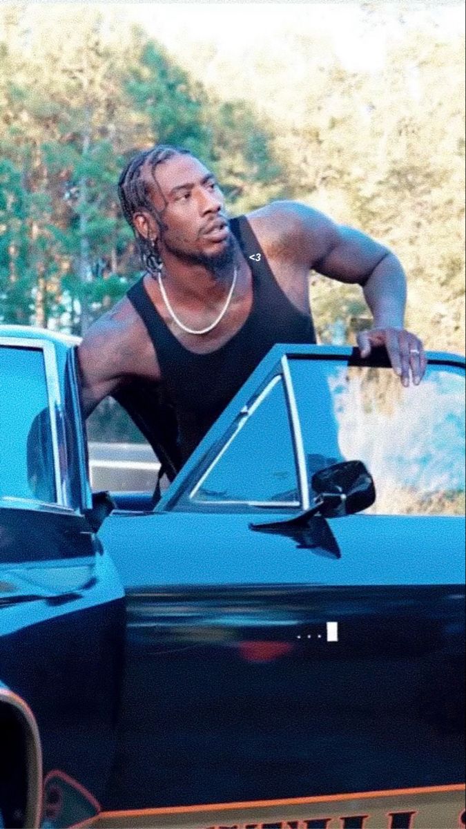 a man leaning on the hood of a blue car