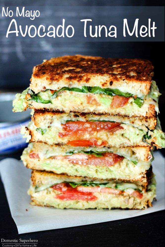 three sandwiches stacked on top of each other with tomatoes and avocado in the middle