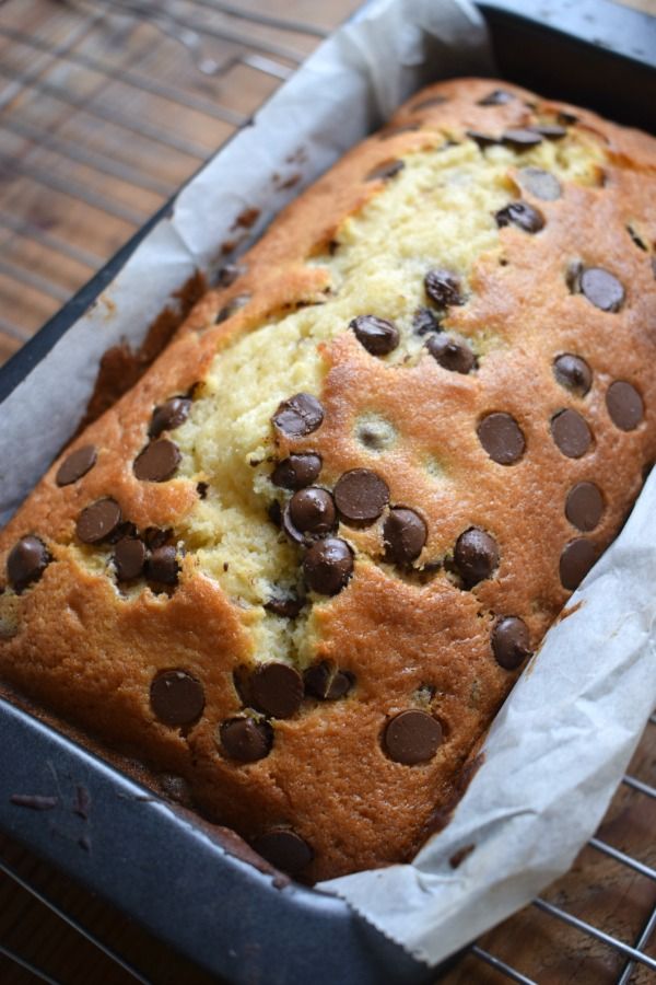 a loaf of cake with chocolate chips on top sitting on a cooling rack in a pan