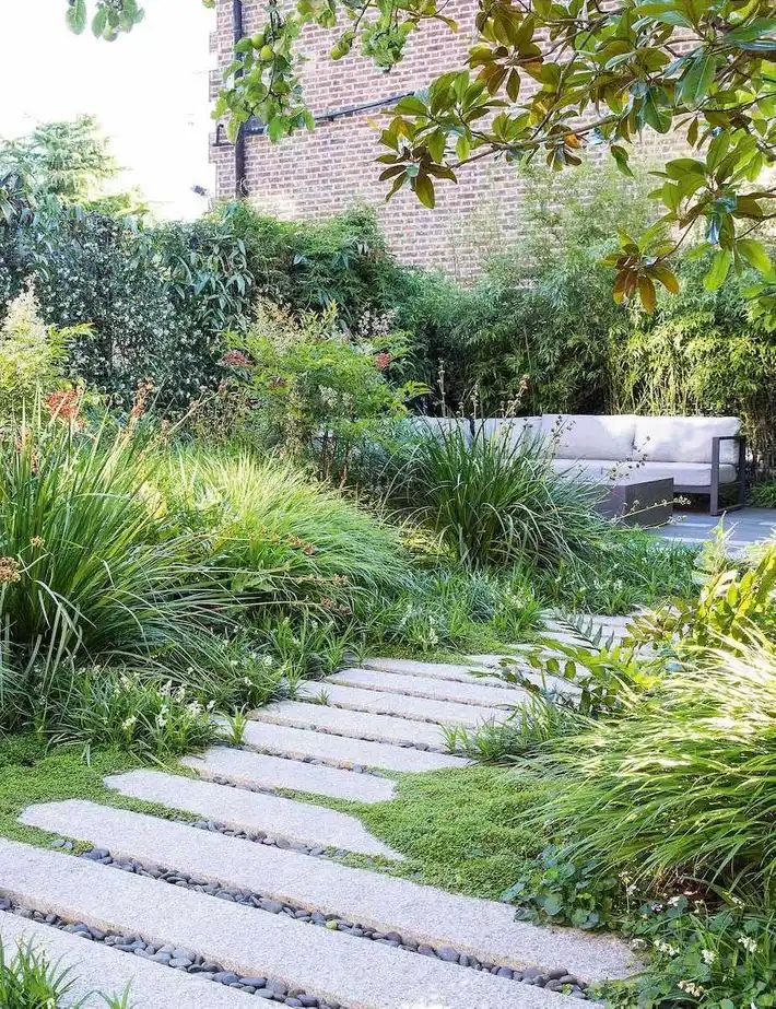 a garden with stone steps leading to a bench