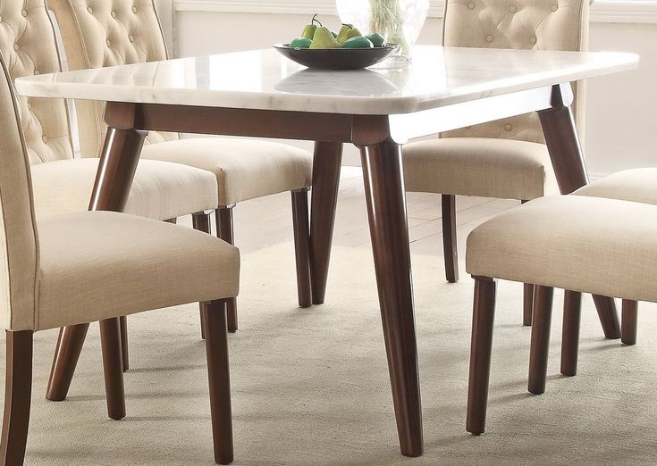 a dining room table with chairs and a bowl of fruit on it's side