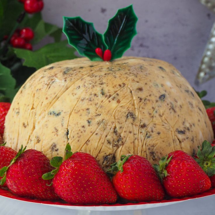 there is a cake with strawberries on the plate next to holly leaves and berries