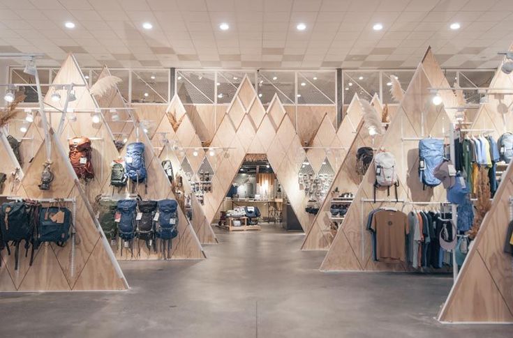 the inside of a clothing store with lots of clothes hanging on wooden racks and shelves