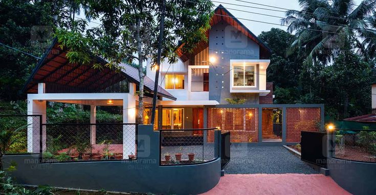 the house is surrounded by trees and greenery at night, with its lights on