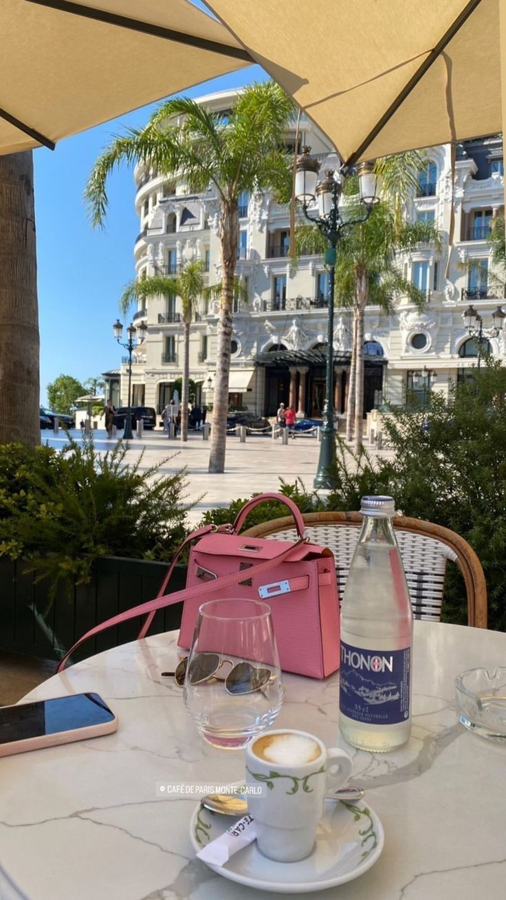 a table that has some drinks on it and an umbrella in front of the building