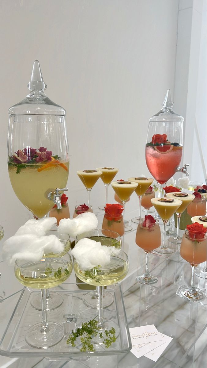 a table topped with lots of glasses filled with different types of drinks and desserts