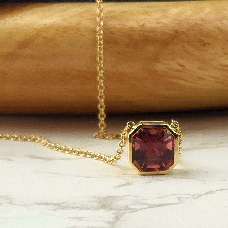 This simple yet glamorous Rhodolite Garnet Necklace is sure to be your favorite. Simple and tailored, it features clean lines and a slightly purplish-red stone that's sure to set off any outfit. Formal Ruby Gemstone Necklaces, Classic Ruby Necklaces For Formal Occasions, Formal Ruby Gemstone Necklace, Formal Yellow Gold Garnet Necklaces, Formal Yellow Gold Garnet Necklace, Classic Ruby Gemstone Necklace, Elegant Octagon Gemstone Necklace, Formal Garnet Fine Jewelry Necklace, Elegant Yellow Gold Garnet Necklace