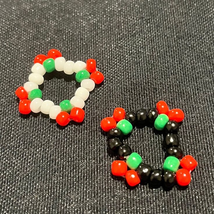 two pieces of beaded jewelry sitting on top of a gray cloth covered floor next to each other