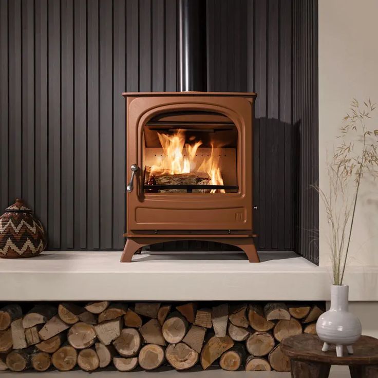 a wood burning stove sitting on top of a white counter next to a pile of logs