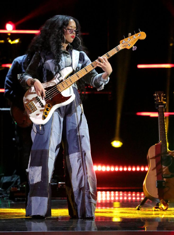 a woman holding a bass guitar on stage