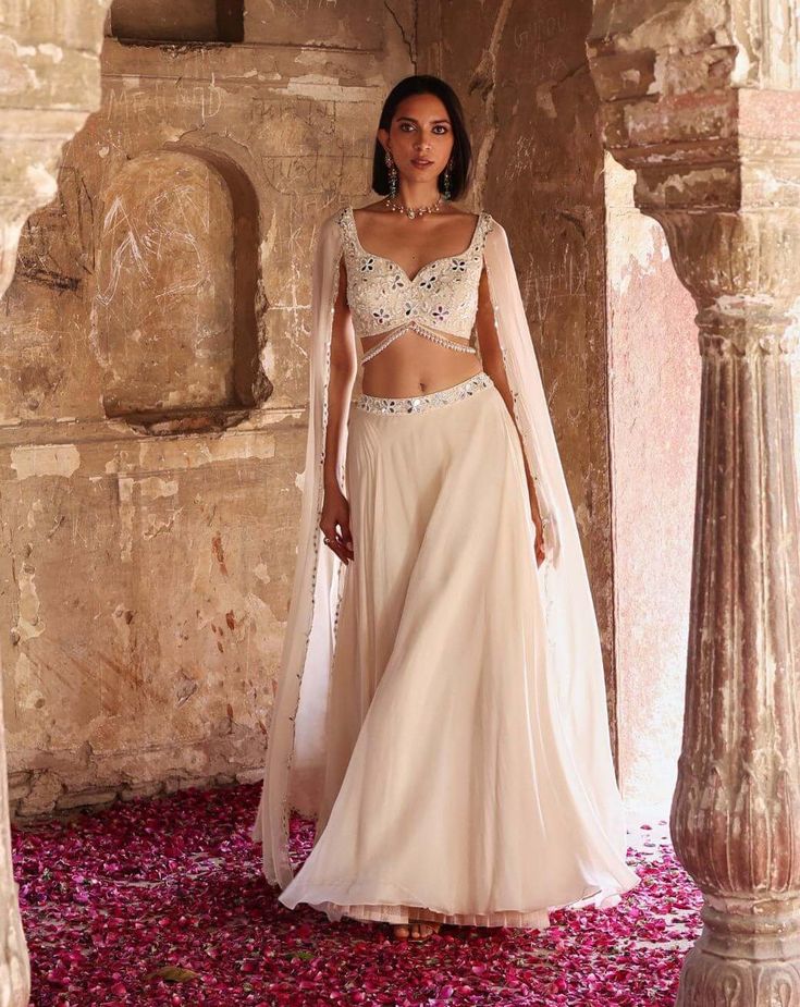 Indulge in sophistication with this embellished choli featuring attached flared sleeves, perfectly paired with a circular skirt adorned with an embellished belt and can-can detailing. This ensemble epitomizes elegance, offering a seamless blend of traditional charm and contemporary flair. Make a statement at any event or celebration with this exquisite outfit that exudes grace and style. Glamorous Designer Palazzo Set With Sheer Dupatta, Elegant Georgette Skirt Set For Reception, Elegant Georgette Skirt Set For Party, Elegant Hand-embellished Georgette Anarkali Set, Elegant Hand Embellished Georgette Anarkali Set, Elegant Lehenga With Sheer Dupatta, Elegant Hand Embellished Anarkali Set For Reception, Elegant Floor-length Choli With Sheer Dupatta, Bollywood Designer Dress With Cape Sleeves