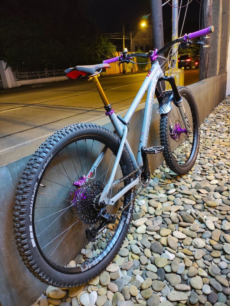 a bike is parked on the side of a wall near some rocks and gravel at night