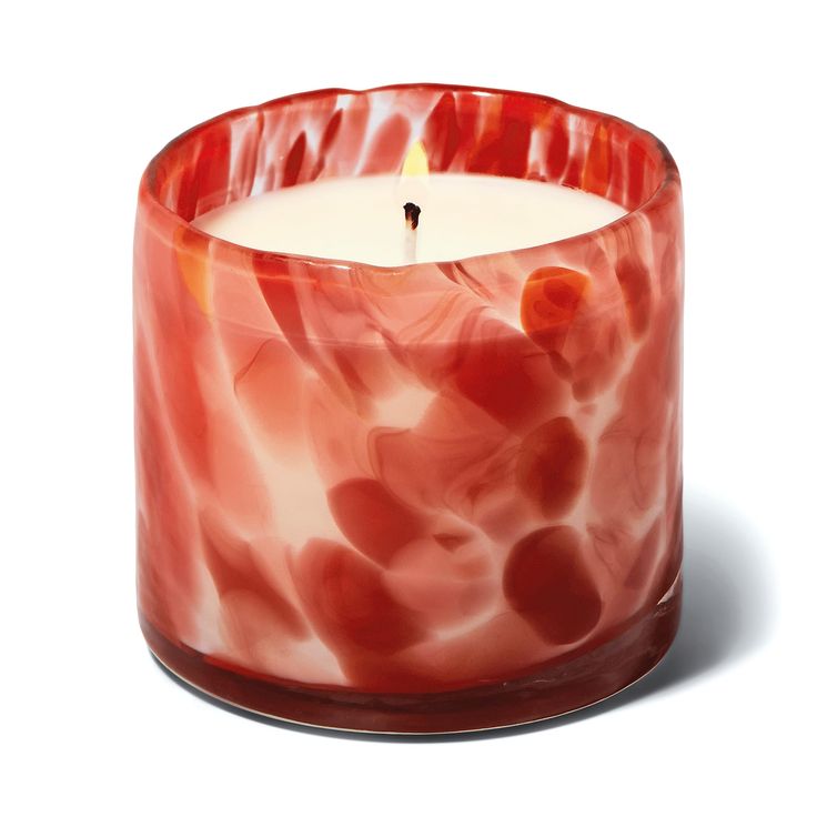 a candle that is sitting in front of a white background with red swirls on it