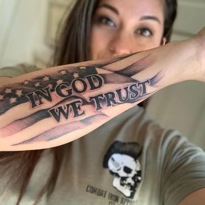 a woman with a tattoo on her arm that says in god we trust and an american flag