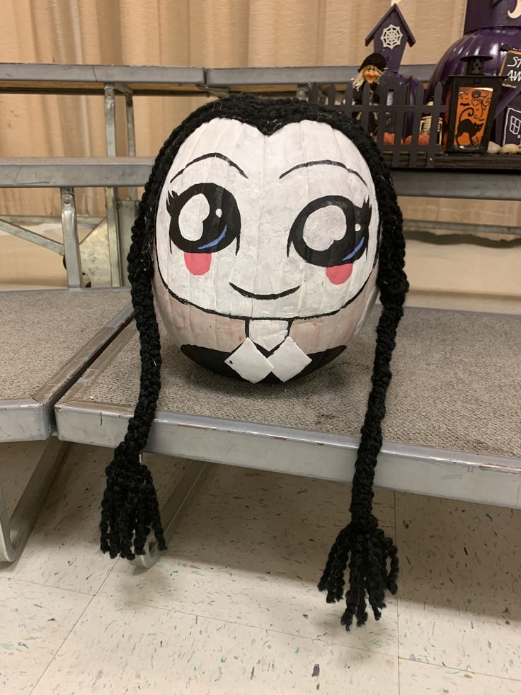 a white ball with black hair sitting on top of a metal shelf next to a wall