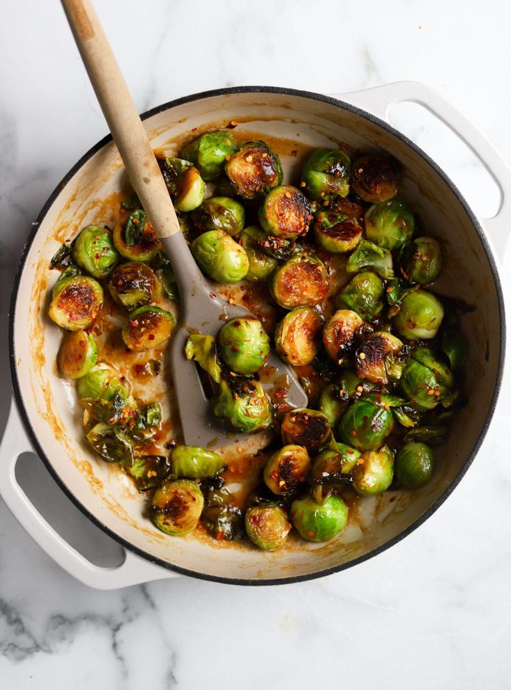 brussel sprouts in a skillet with a wooden spoon on the side