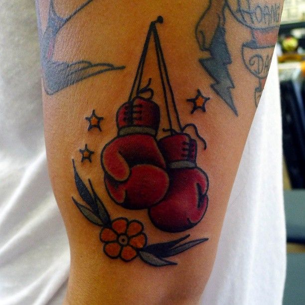 a man with a tattoo on his arm that has two boxing gloves hanging from it