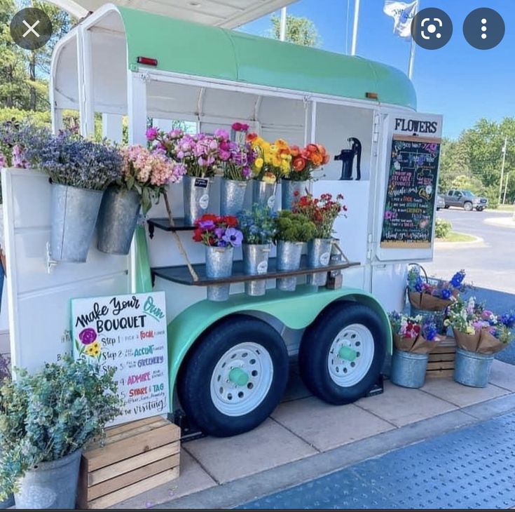 an ice cream truck with flowers on the side and plants in buckets at the back