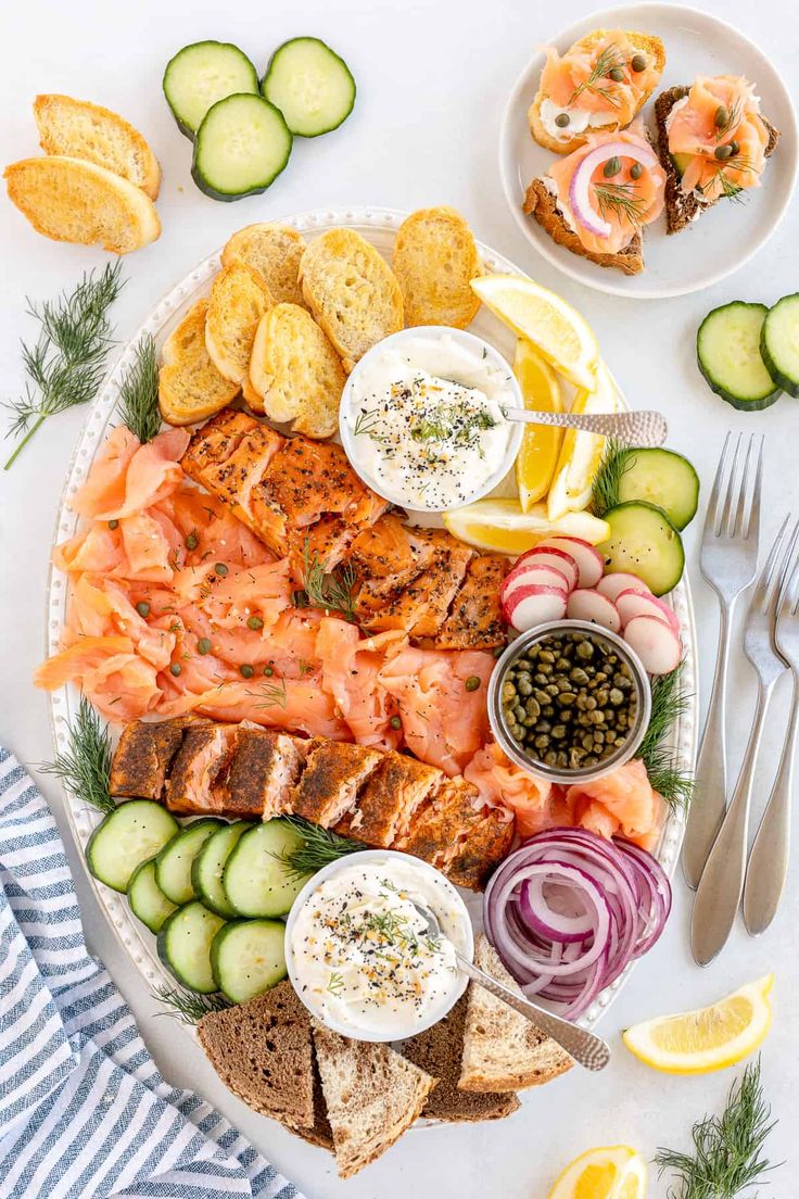 the salmon platter with lemons, cucumbers and pickles on it