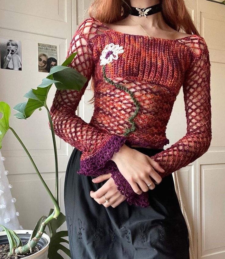 a woman with red hair wearing a dress and holding a plant in front of her