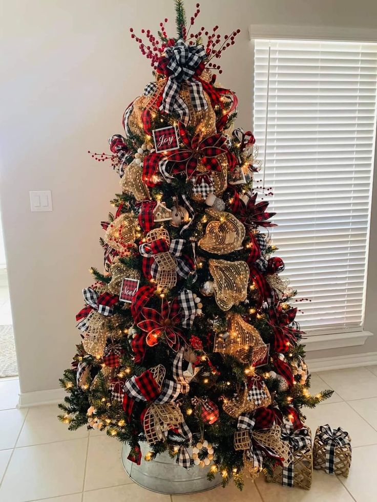 a decorated christmas tree with red, black and gold ornaments in a metal pot on the floor