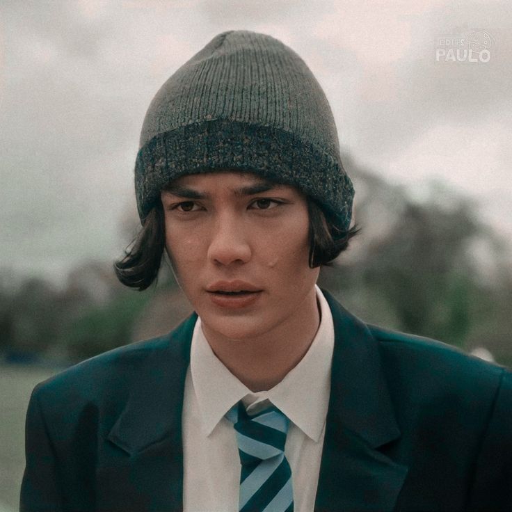 a man wearing a suit and tie with a green knitted hat on his head