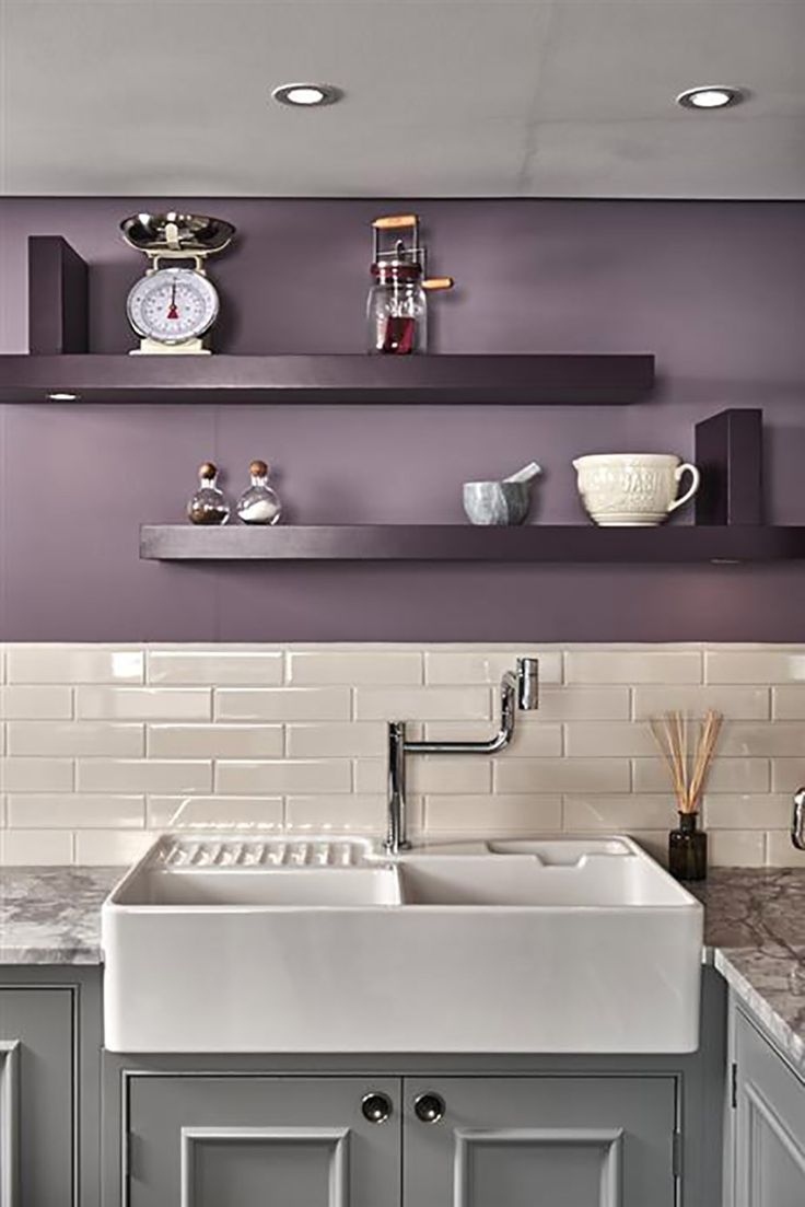 a kitchen with gray cabinets and white counter tops, along with shelves above the sink