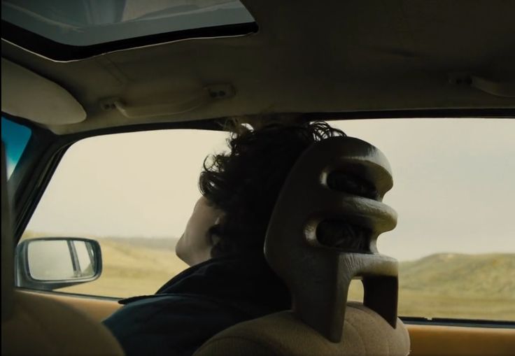 a man sitting in the back seat of a car with his head out the window