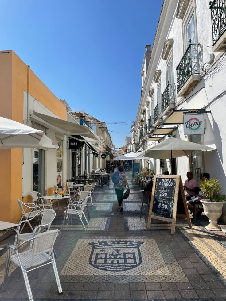 an empty sidewalk with tables and chairs on it