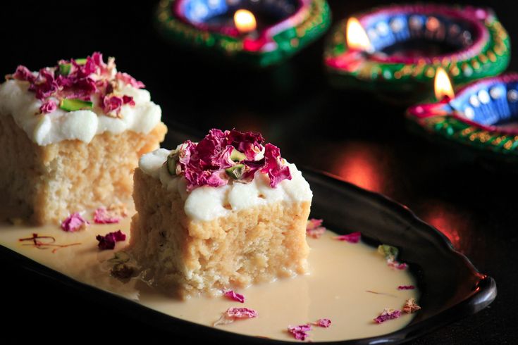 two pieces of cake sitting on top of a black plate with white frosting and pink flowers