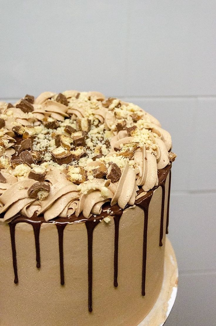 a chocolate cake with white frosting and nuts on top