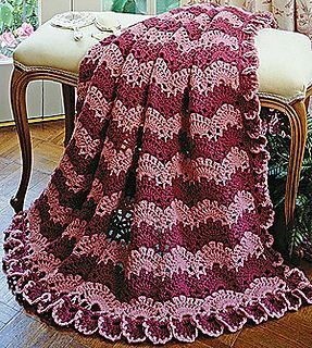 a pink crocheted blanket sitting on top of a wooden chair next to a window