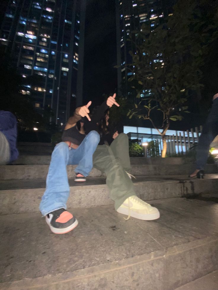 two people sitting on steps with their hands in the air and one person pointing at something