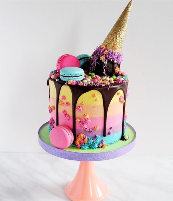 there is a colorful cake with chocolate icing and decorations on it, including an ice cream cone