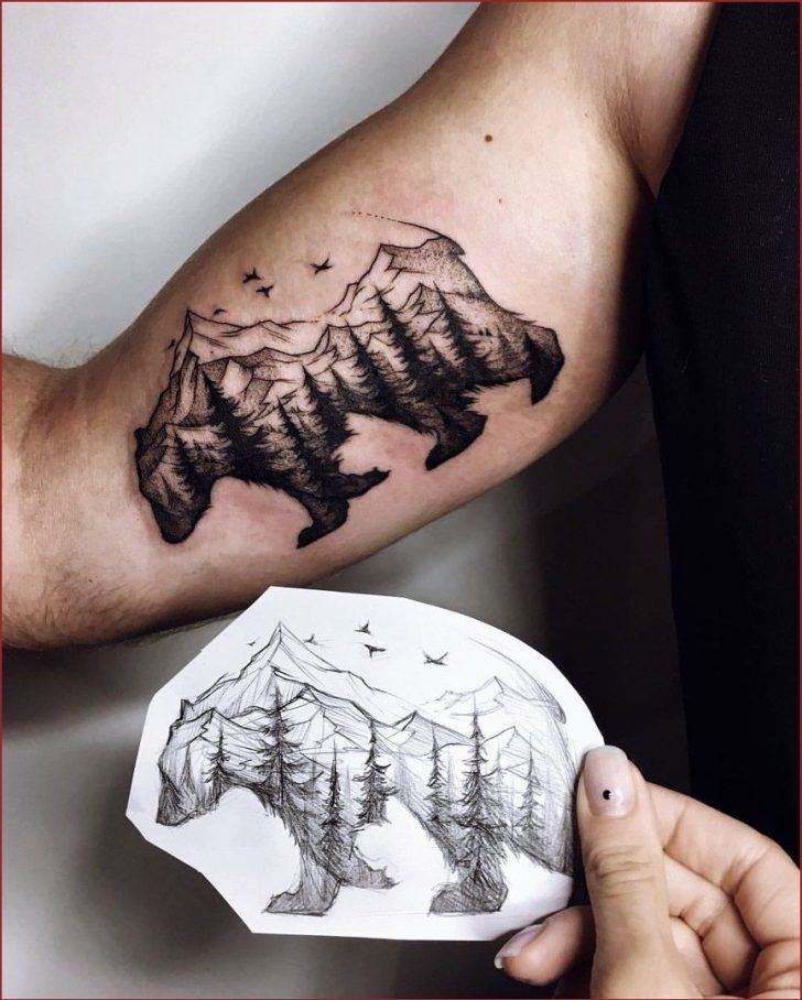 a man's arm with a mountain and forest tattoo on the left side of his arm