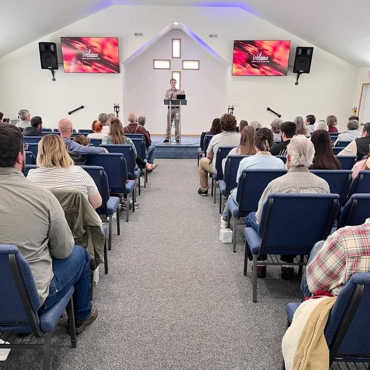 people are sitting in chairs and listening to a man giving a speech at an event