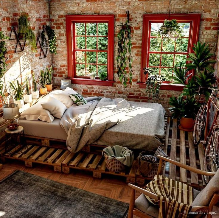 a bed made out of pallets in front of two windows with plants on them