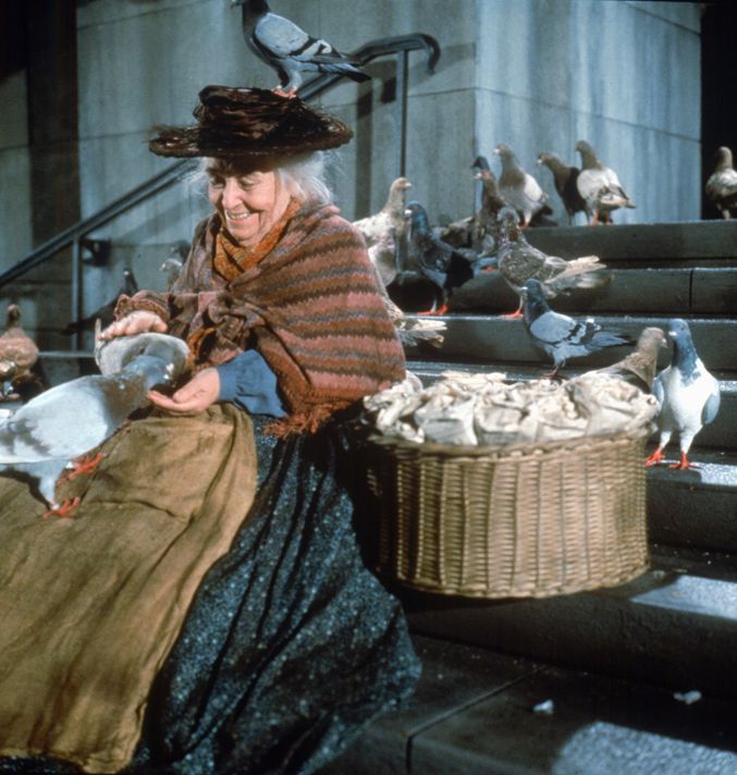 an old woman is sitting on the steps with pigeons and birds in front of her