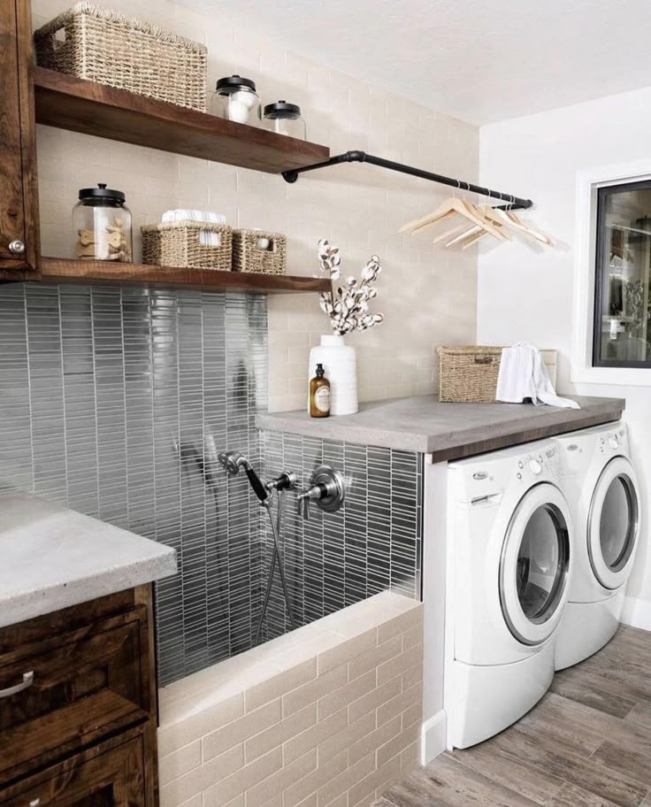 a washer and dryer in a small room with shelves on the wall above them