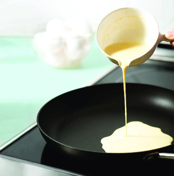 a person pouring sauce on top of a frying pan