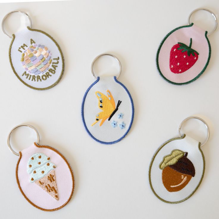 four embroidered keychains with different designs on them, one is for children and the other is for adults