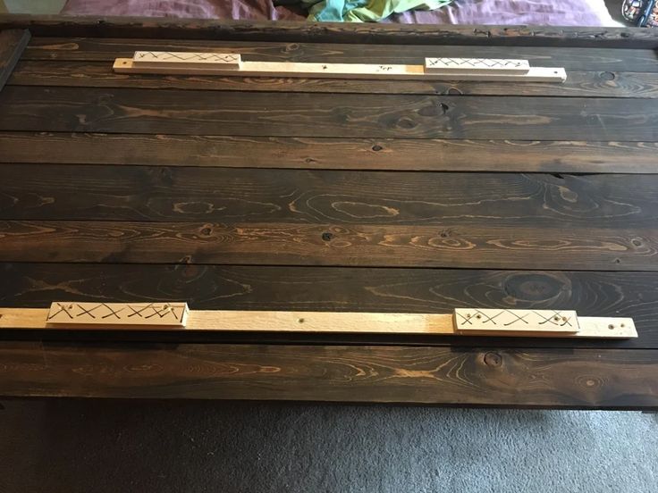 a bed frame made out of wooden planks with metal handles on each one side