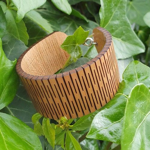 a wooden bracelet is sitting on some green leaves