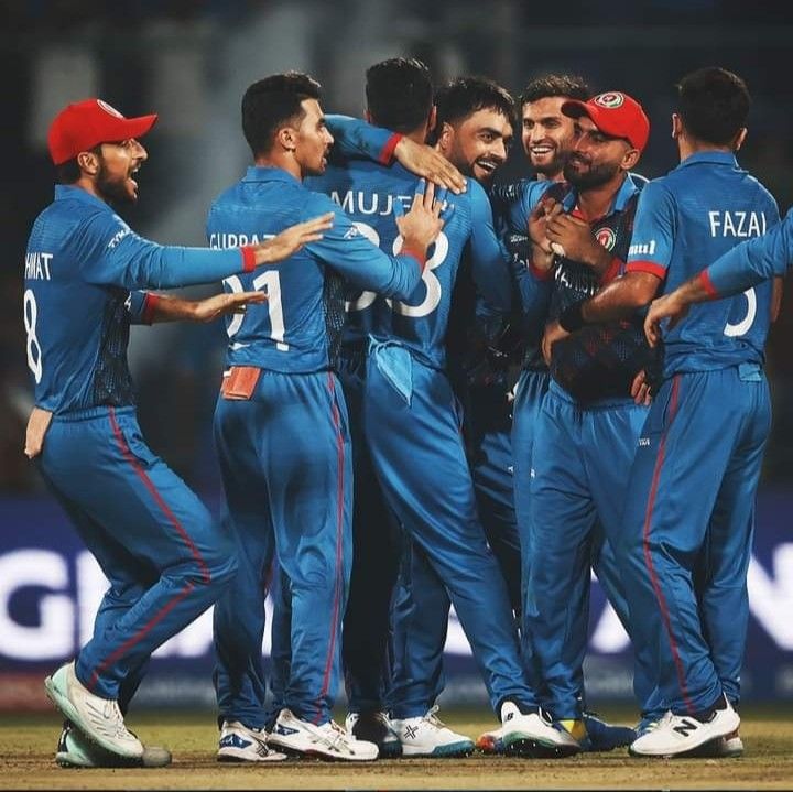 a group of men standing next to each other on top of a field wearing blue uniforms