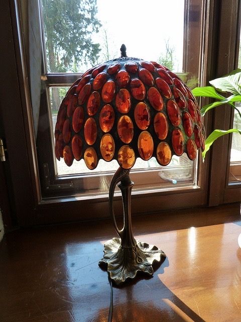 a lamp sitting on top of a table next to a potted plant in front of a window