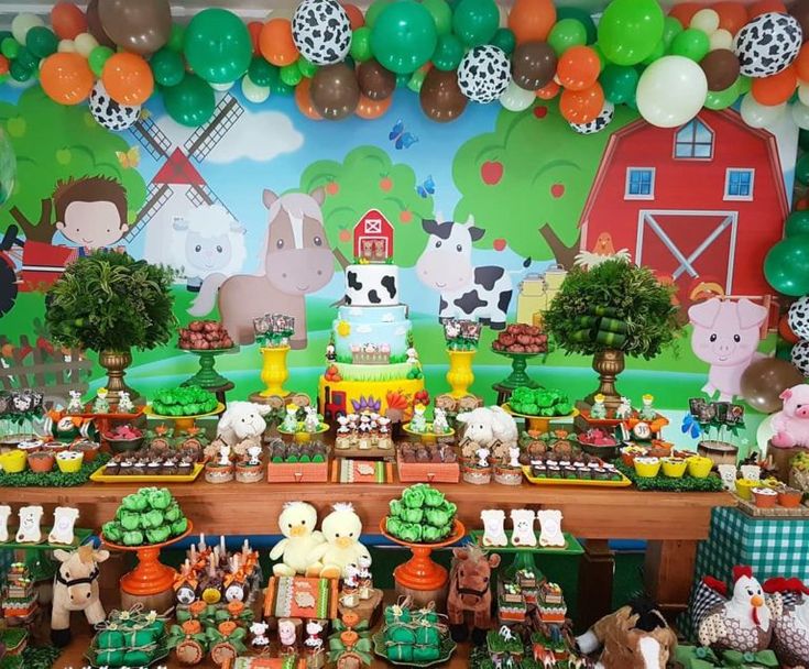 a farm animals themed birthday party with cake and desserts on the table, balloons in the background