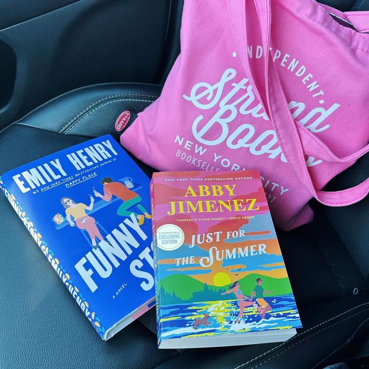 three children's books sitting on the back seat of a car, next to a pink bag